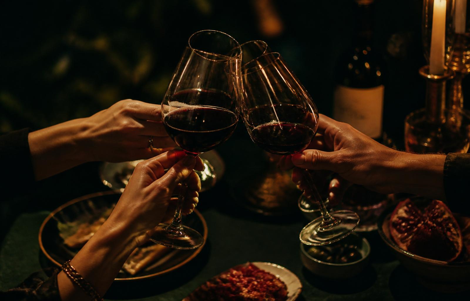 Mãos brindando com taças sobre a mesa, sem rostos visíveis